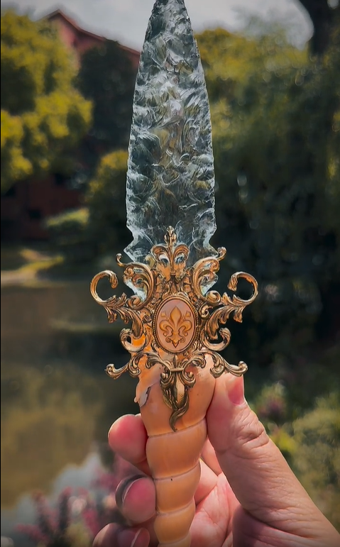Witch Dagger held over water in a natural outdoor setting, emphasizing its connection to ocean magic and elemental rituals.